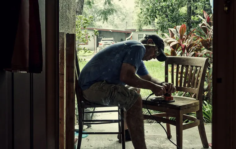 Craftsperson working on a wooden chair as an example of carpentry